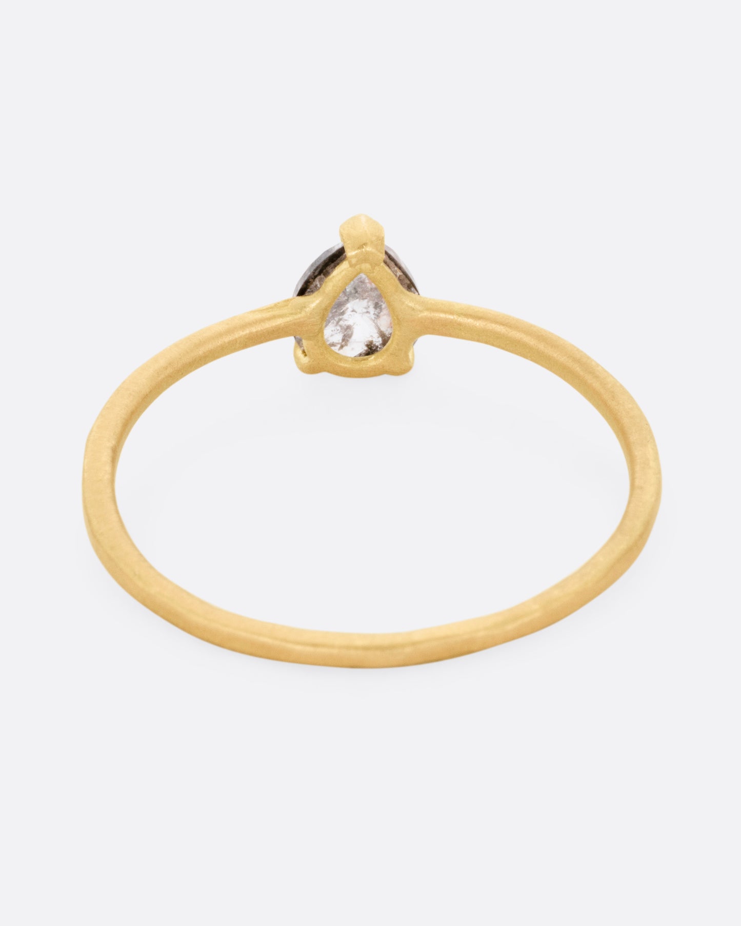 A yellow gold ring with a prong set salt and pepper diamond, flanked by tiny white diamond accents. Shown from the back.