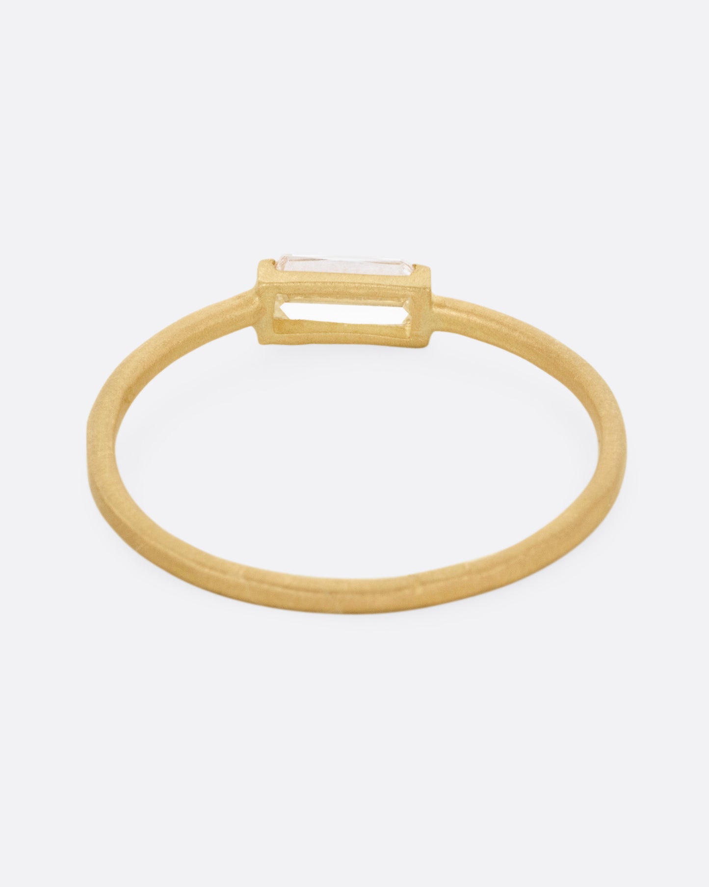 A yellow gold ring with a grey baguette diamond, shown from the back.
