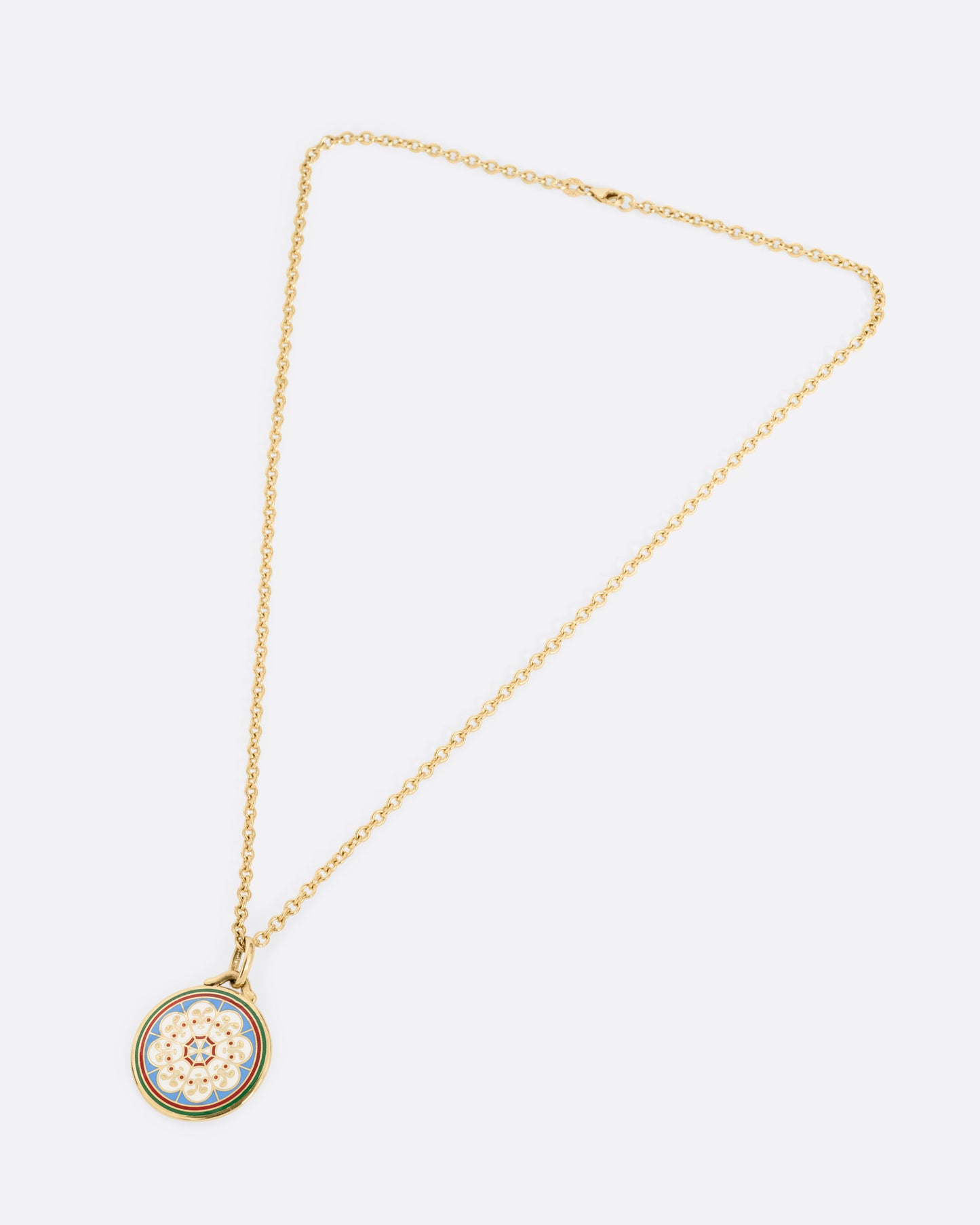 A yellow gold necklace with a circular pendant hanging from it, on it is a circle of white faces in enamel. Shown laying flat.
