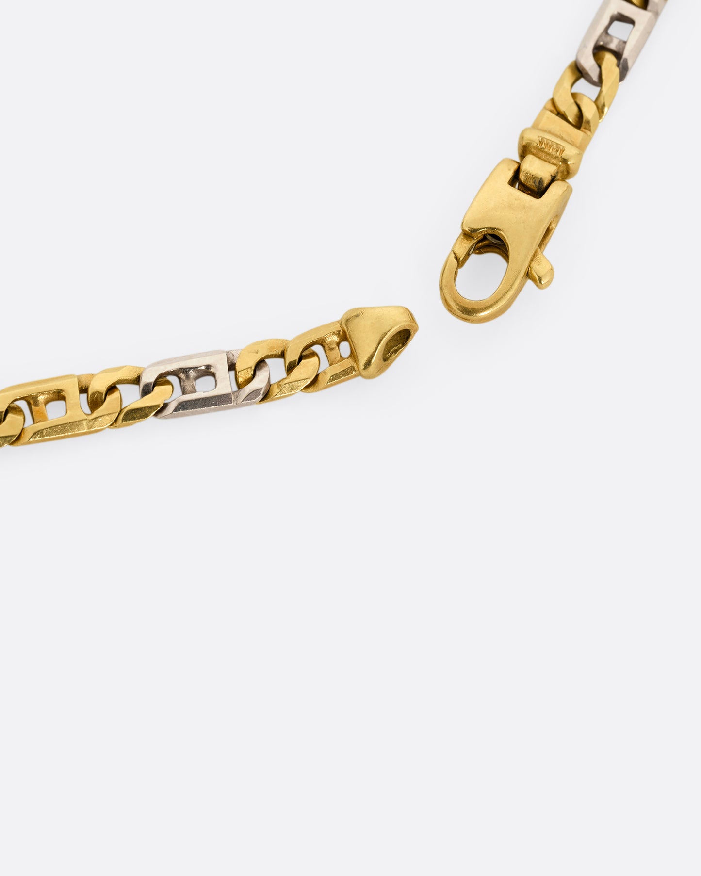 A white and yellow gold geometric flat chain necklace. Shown close up of the clasp.