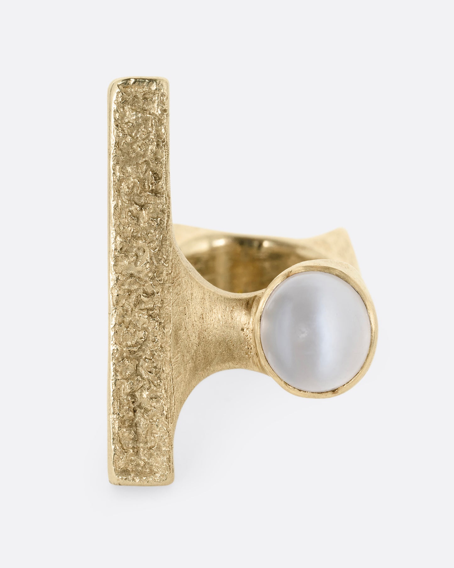 A yellow gold ring with the eye of Horus and a bezel set moonstone on the top. Shown from the top.