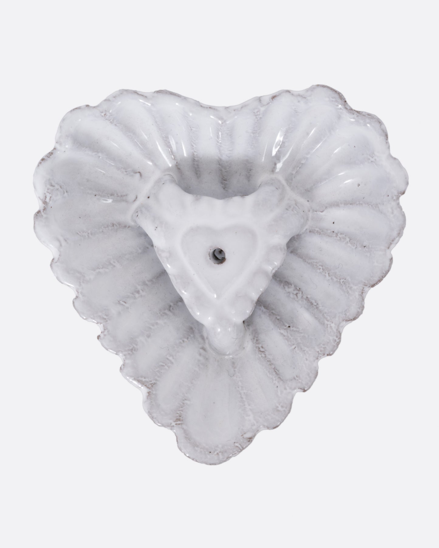 A white heart shaped incense holder, shown from the top.