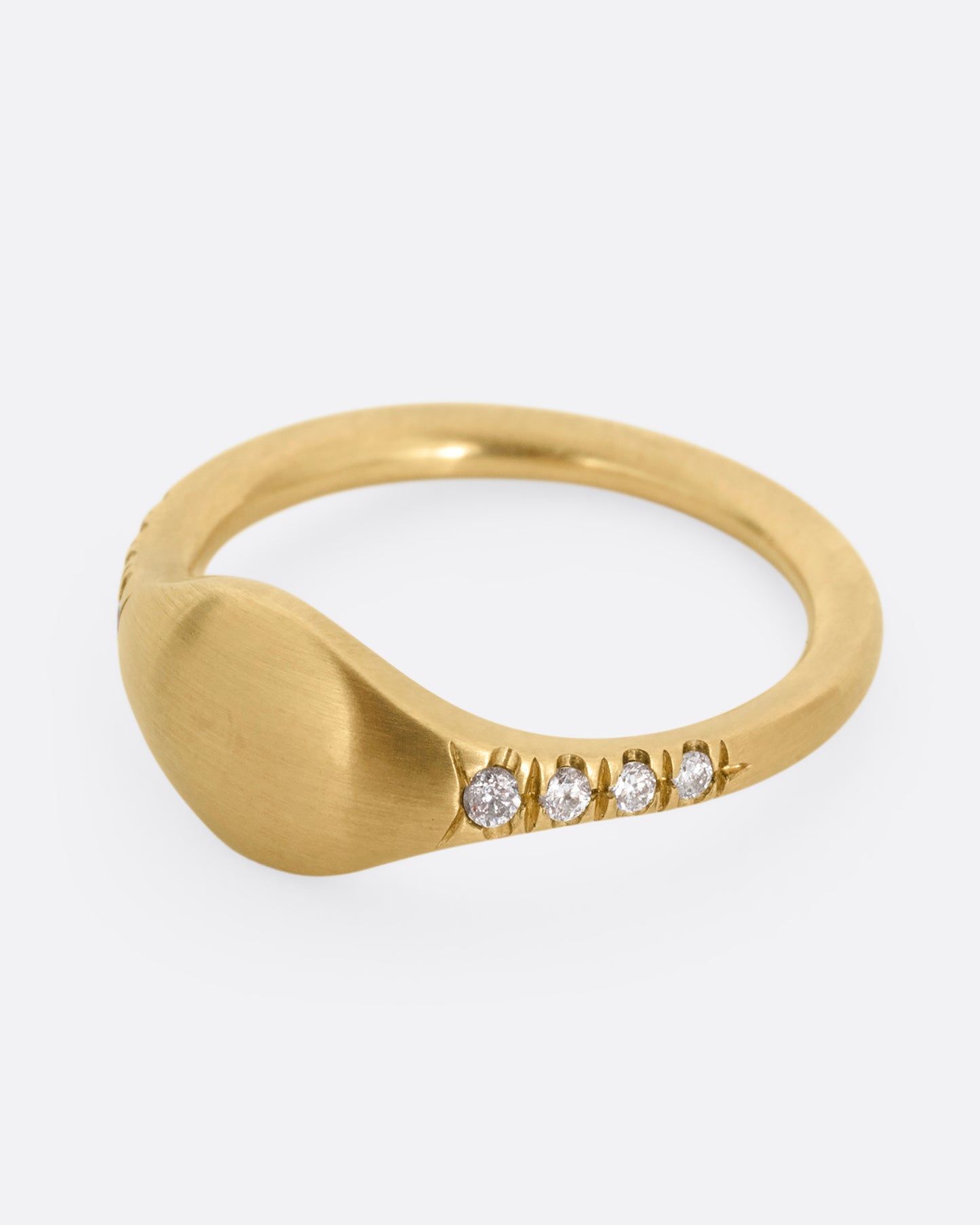 A yellow gold signet ring with diamonds on the shoulders. Shown from the side.