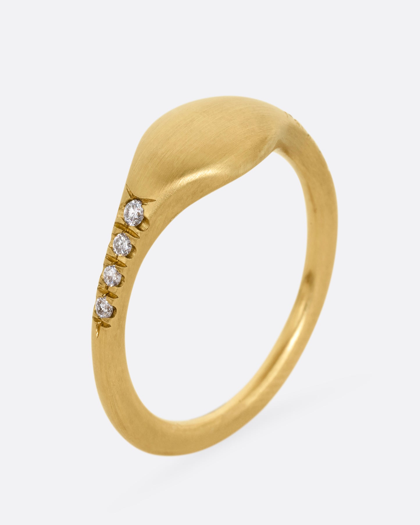 A yellow gold signet ring with diamonds on the shoulders. Shown standing up from the side.