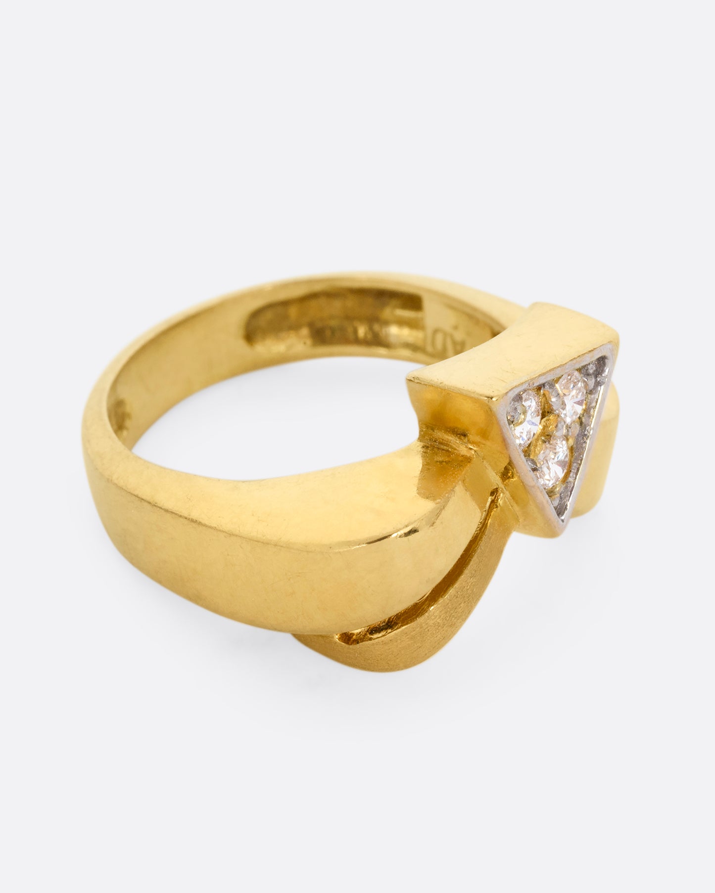 A yellow gold ring with a curvy band and three diamonds set in a triangular shaped setting. Shown from the side.