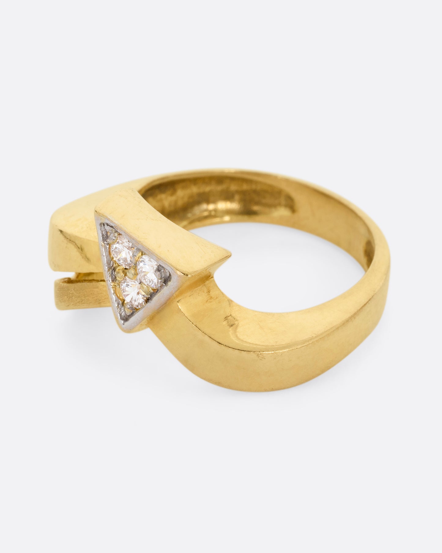 A yellow gold ring with a curvy band and three diamonds set in a triangular shaped setting. Shown from the side.