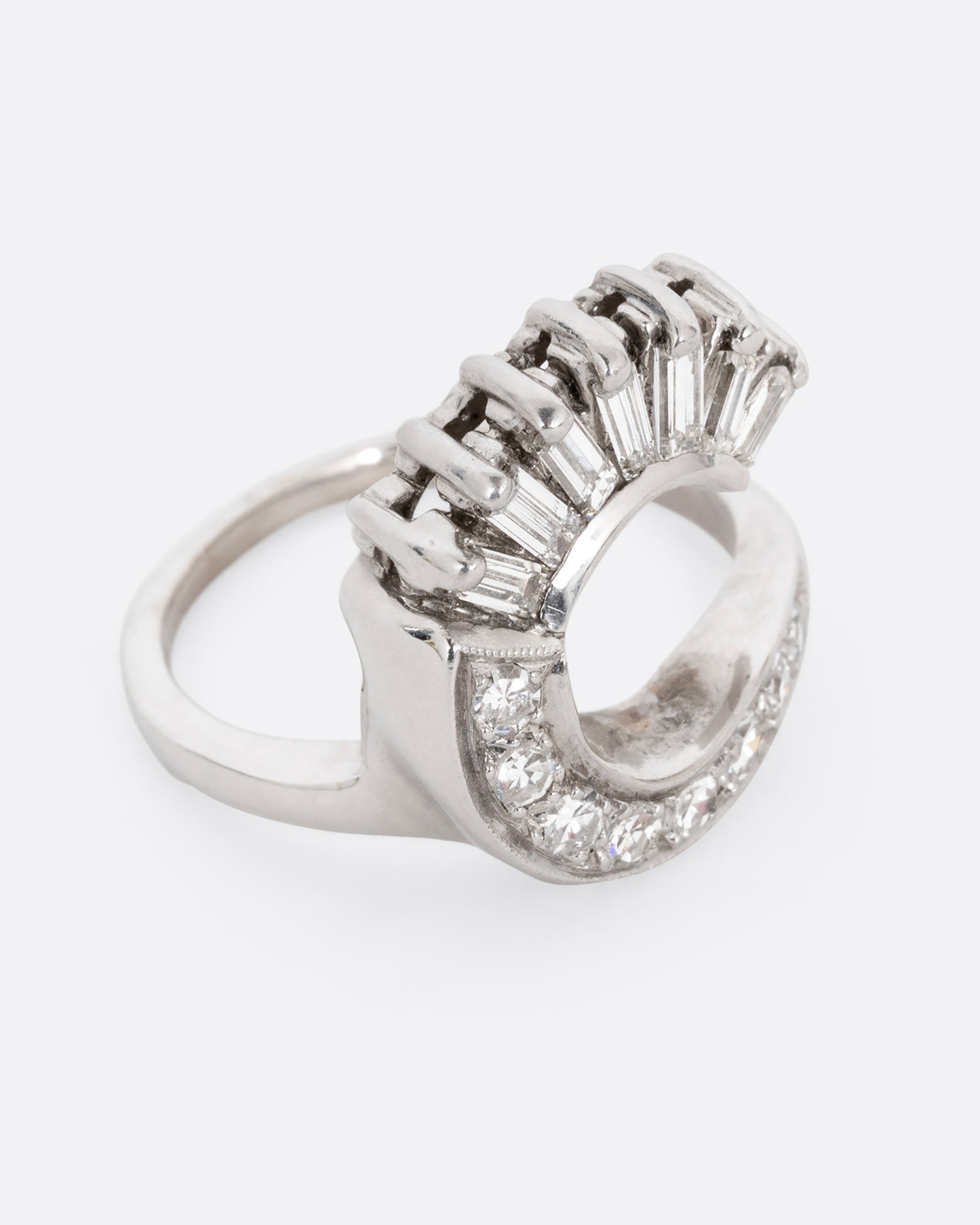 A white gold wave ring with baguette diamonds and round diamonds. Shown diagonally from the front.