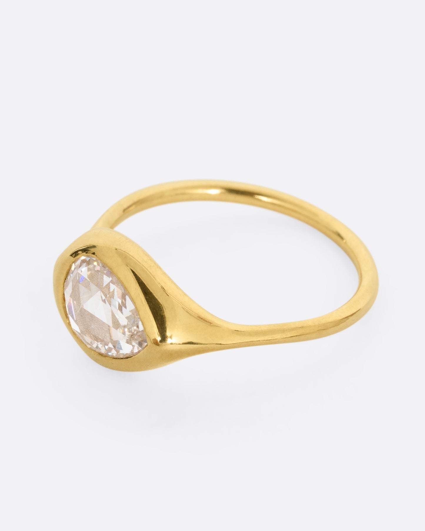 A yellow gold band with a rose cut pear shaped diamond. Shown from the side.
