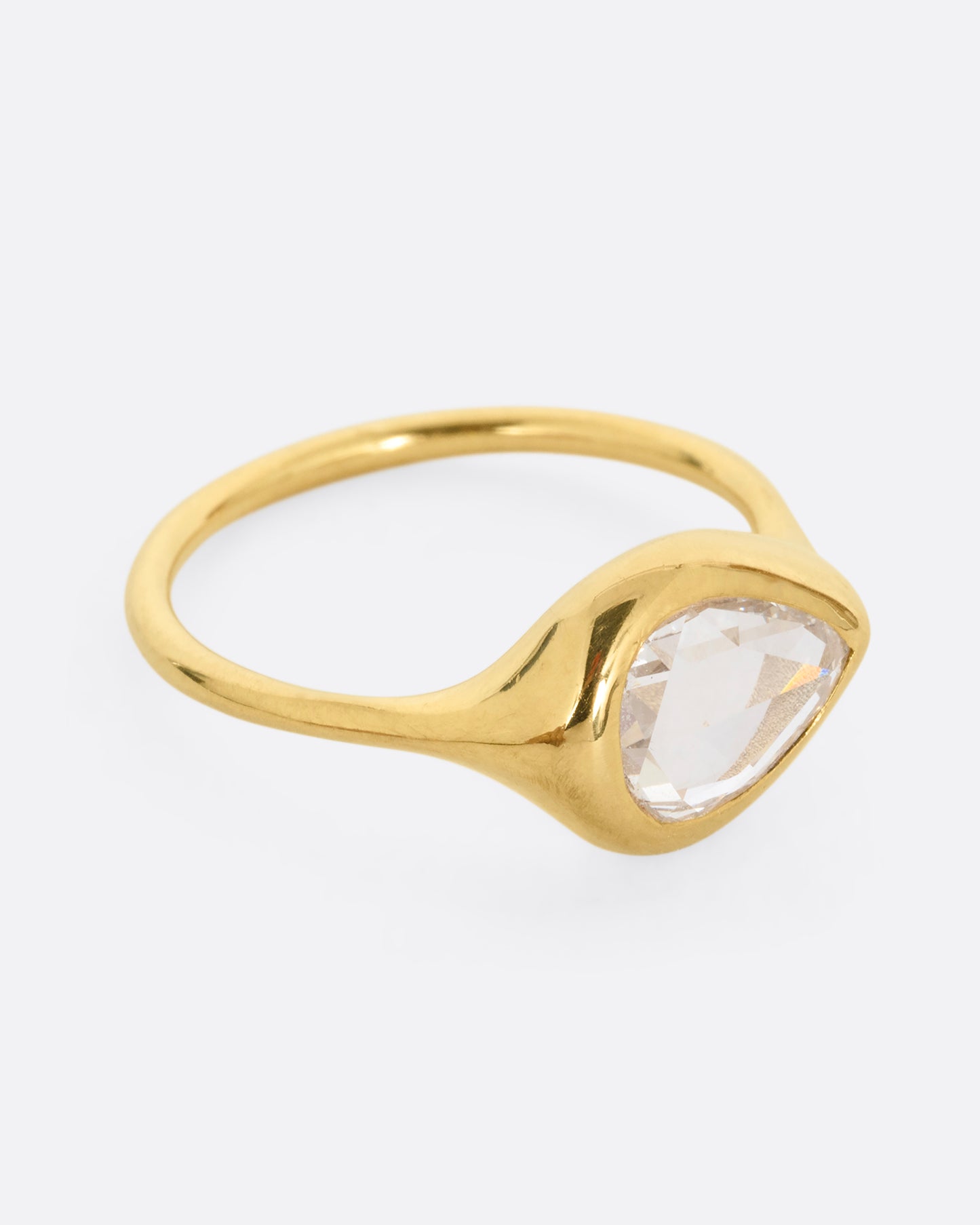 A yellow gold band with a rose cut pear shaped diamond. Shown from the side.