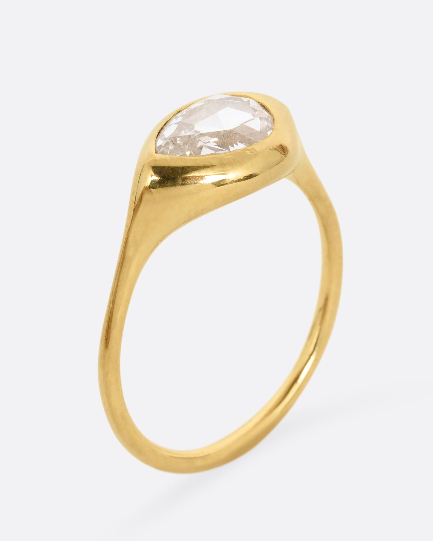 A yellow gold band with a rose cut pear shaped diamond. Shown standing up from the side.
