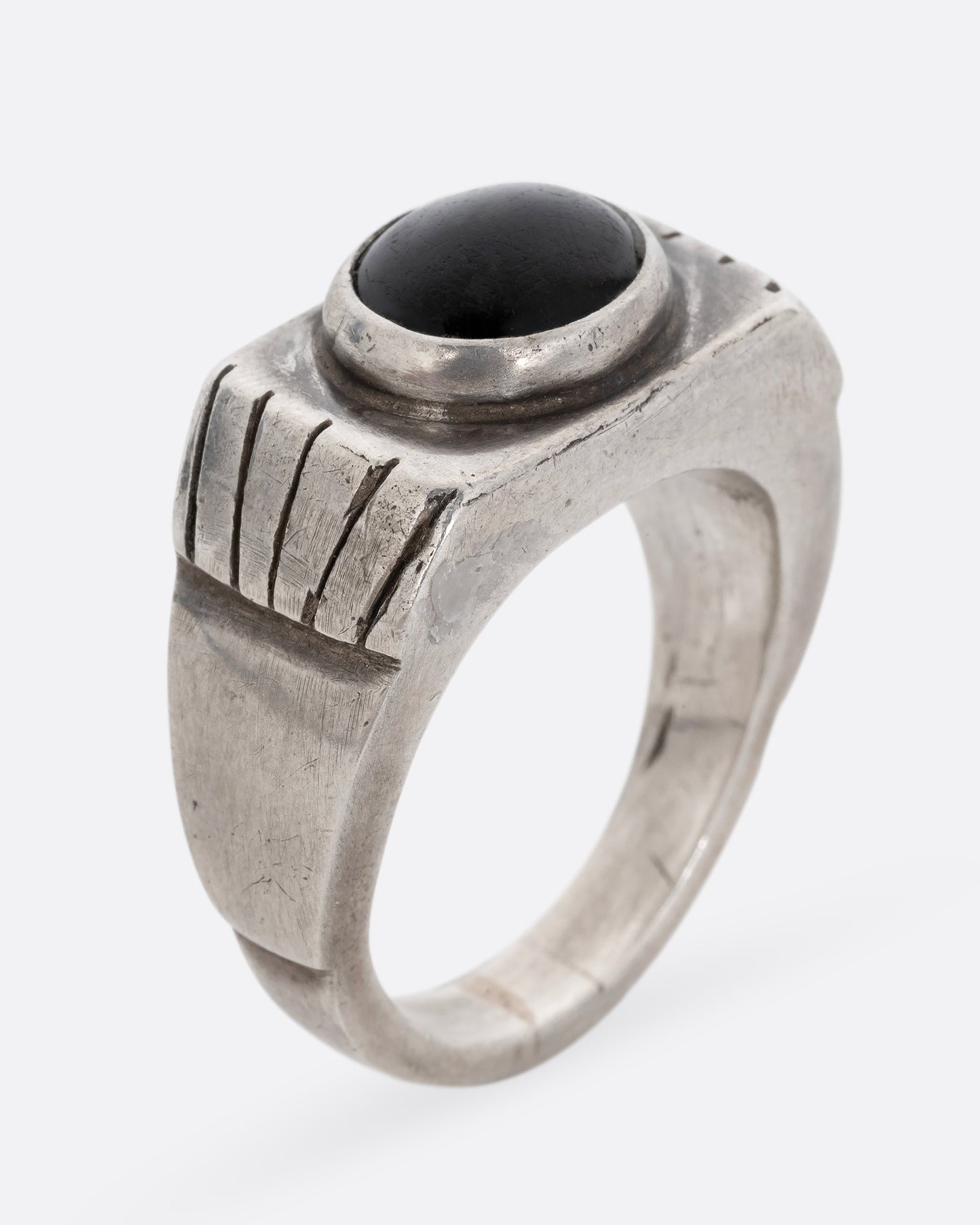 A silver ring with an oval onyx. Shown standing up from the side.