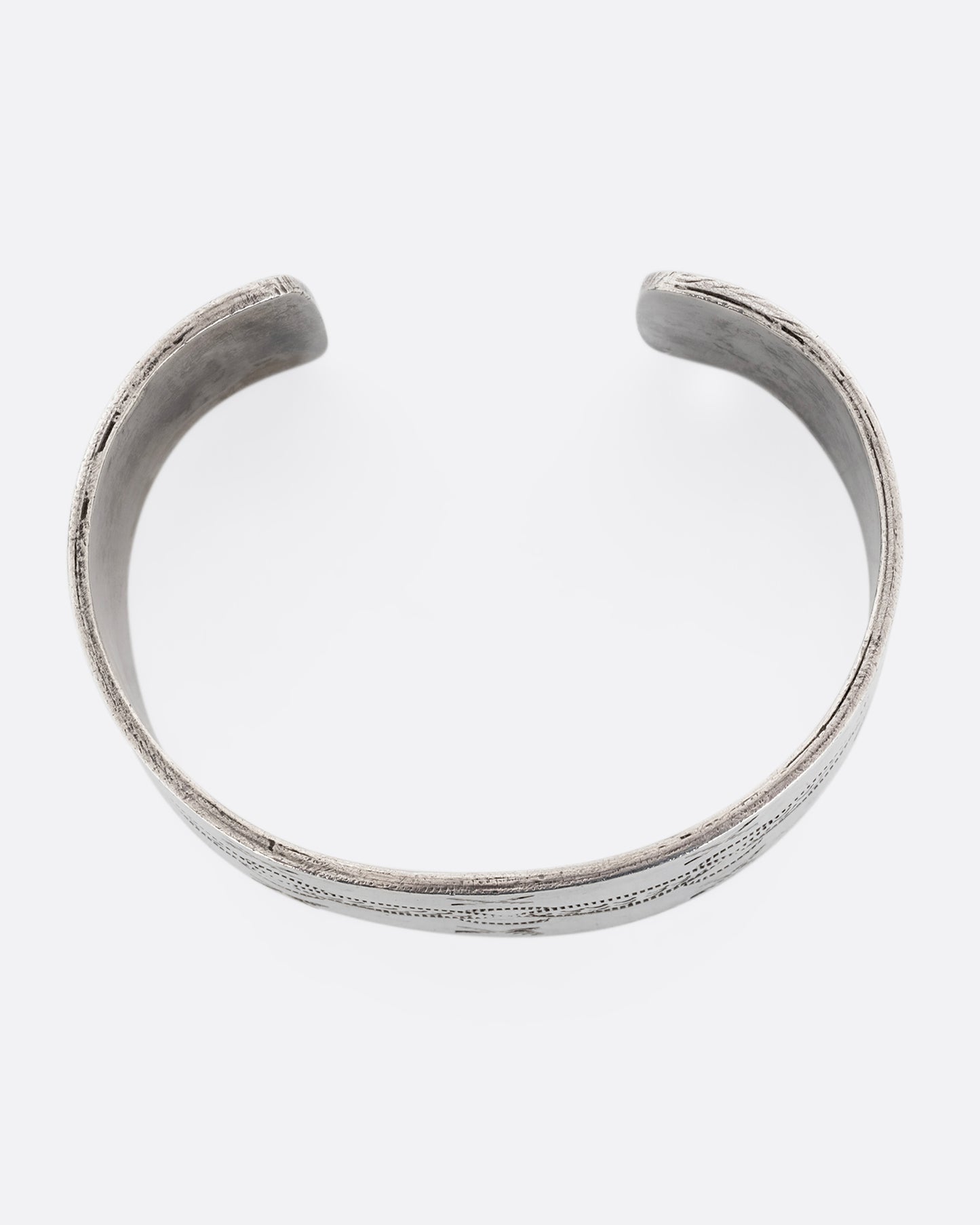 A wide silver cuff bracelet with stamping. Shown from the top.