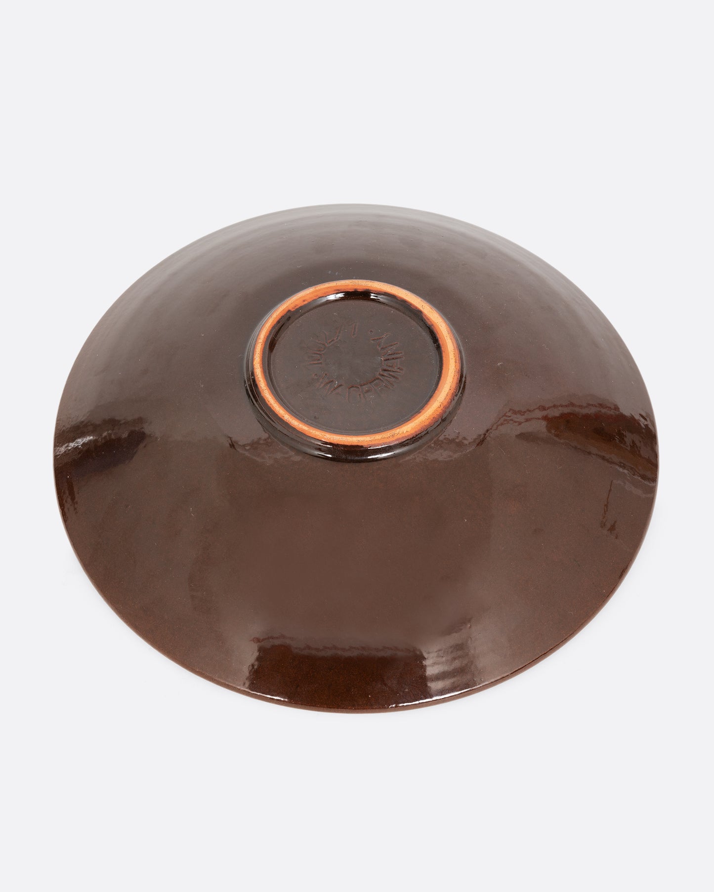 A round serving plate with a brown bottom. Shown from the bottom.