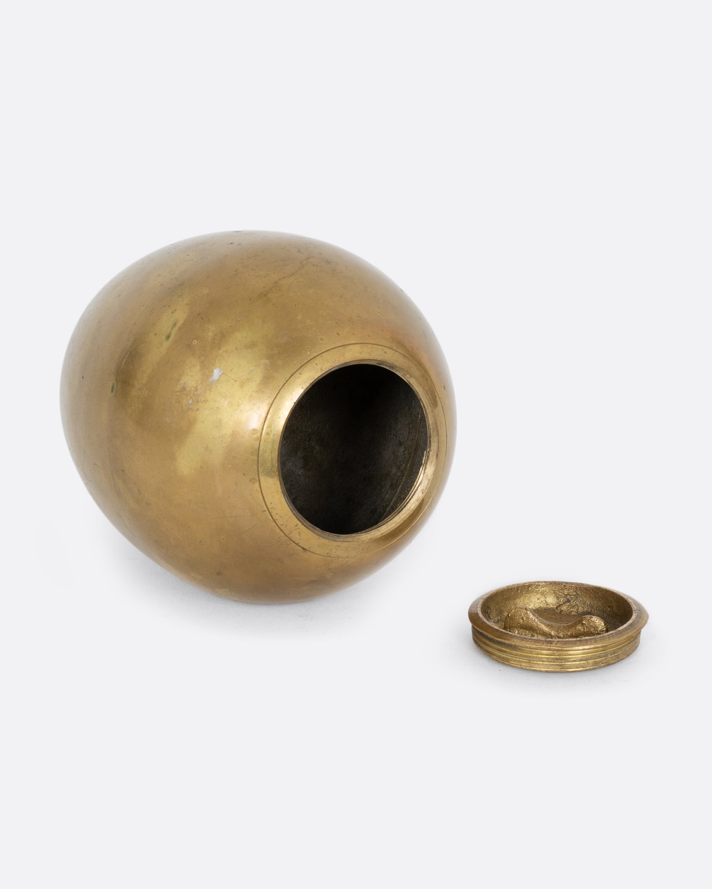 An egg shaped brass bank. Shown open on its side from the bottom.