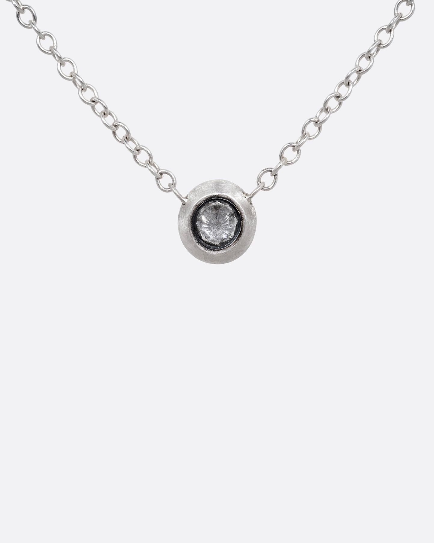 A silver cable chain necklace with a reverse set grey diamond. Shown from the front.
