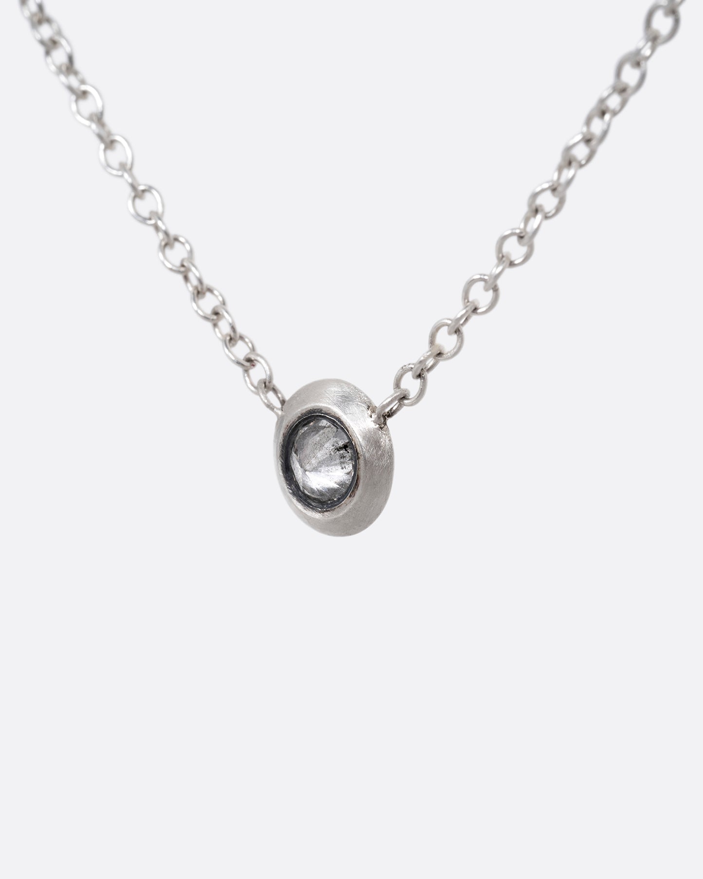 A silver cable chain necklace with a reverse set grey diamond. Shown from the front.