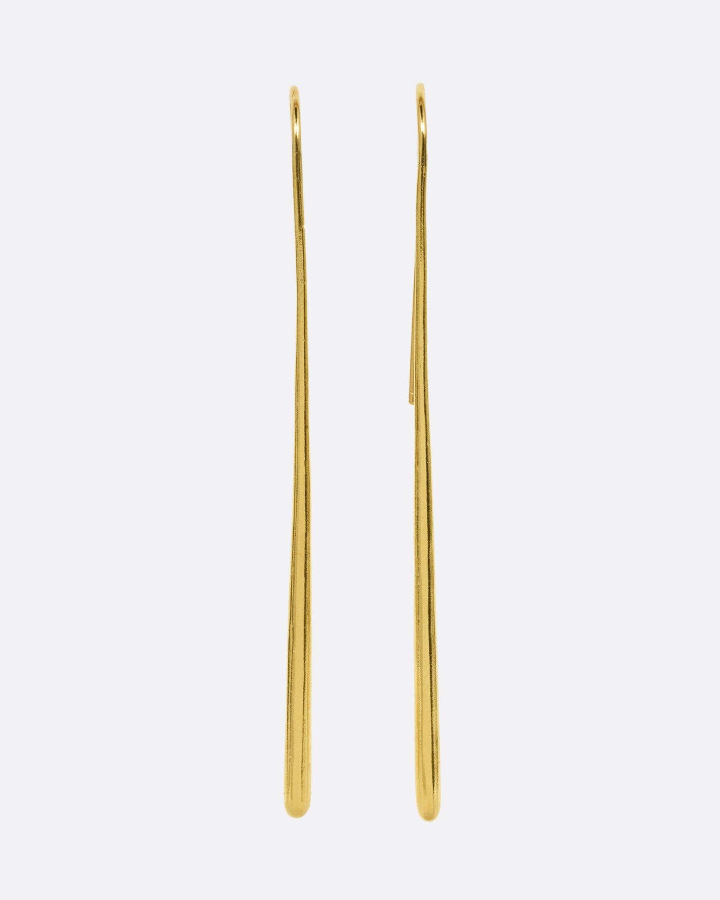 A pair of long narrow yellow gold earrings with a tapered silhouette and ear hooks. Shown from the front.