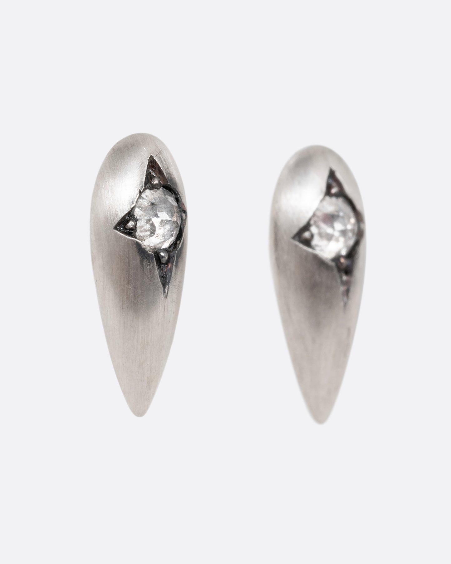 Silver teardrop shaped earrings with rose cut diamonds. Shown from the side.
