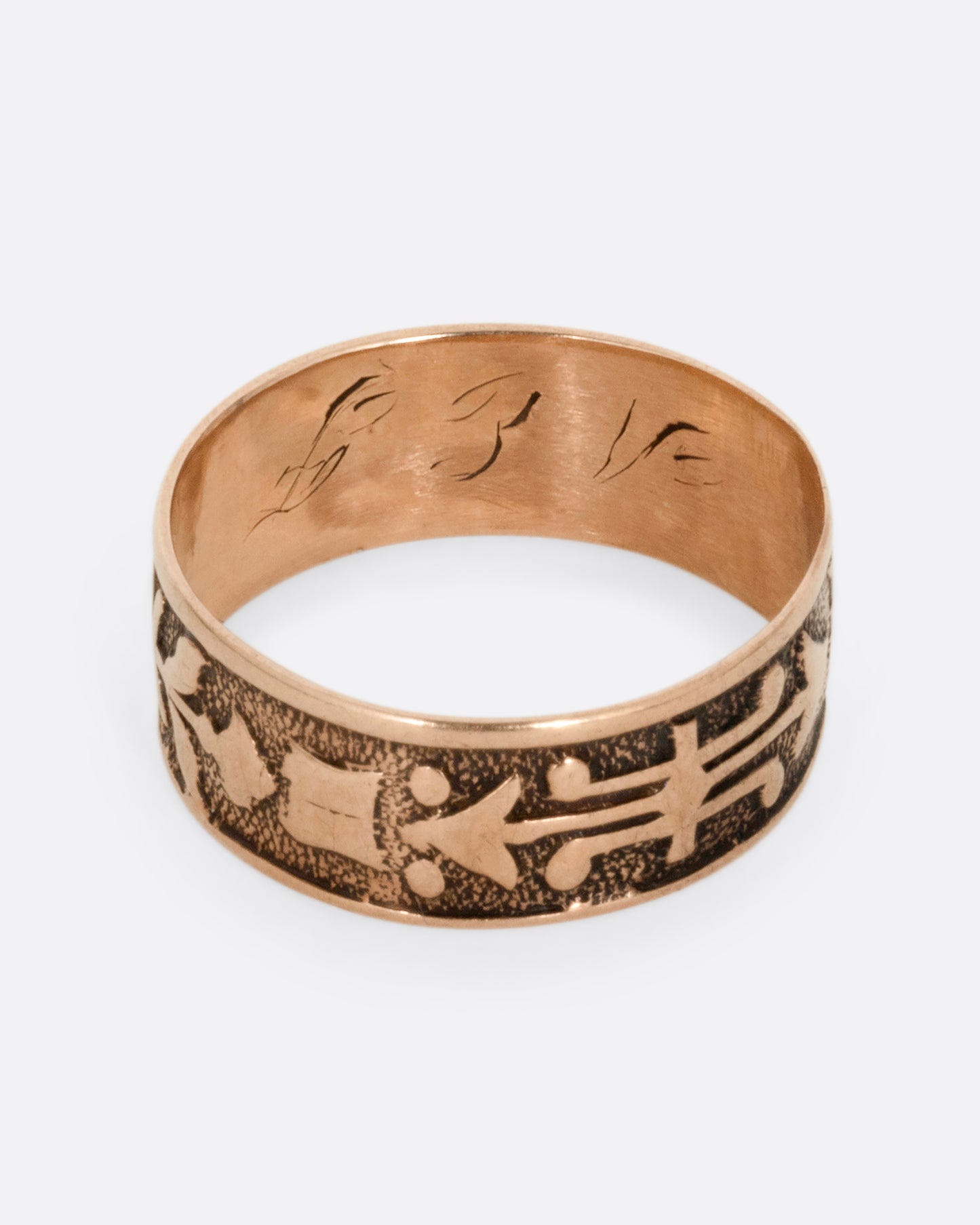 A rose gold cigar band with stamped arrow motif. Shown from the top.