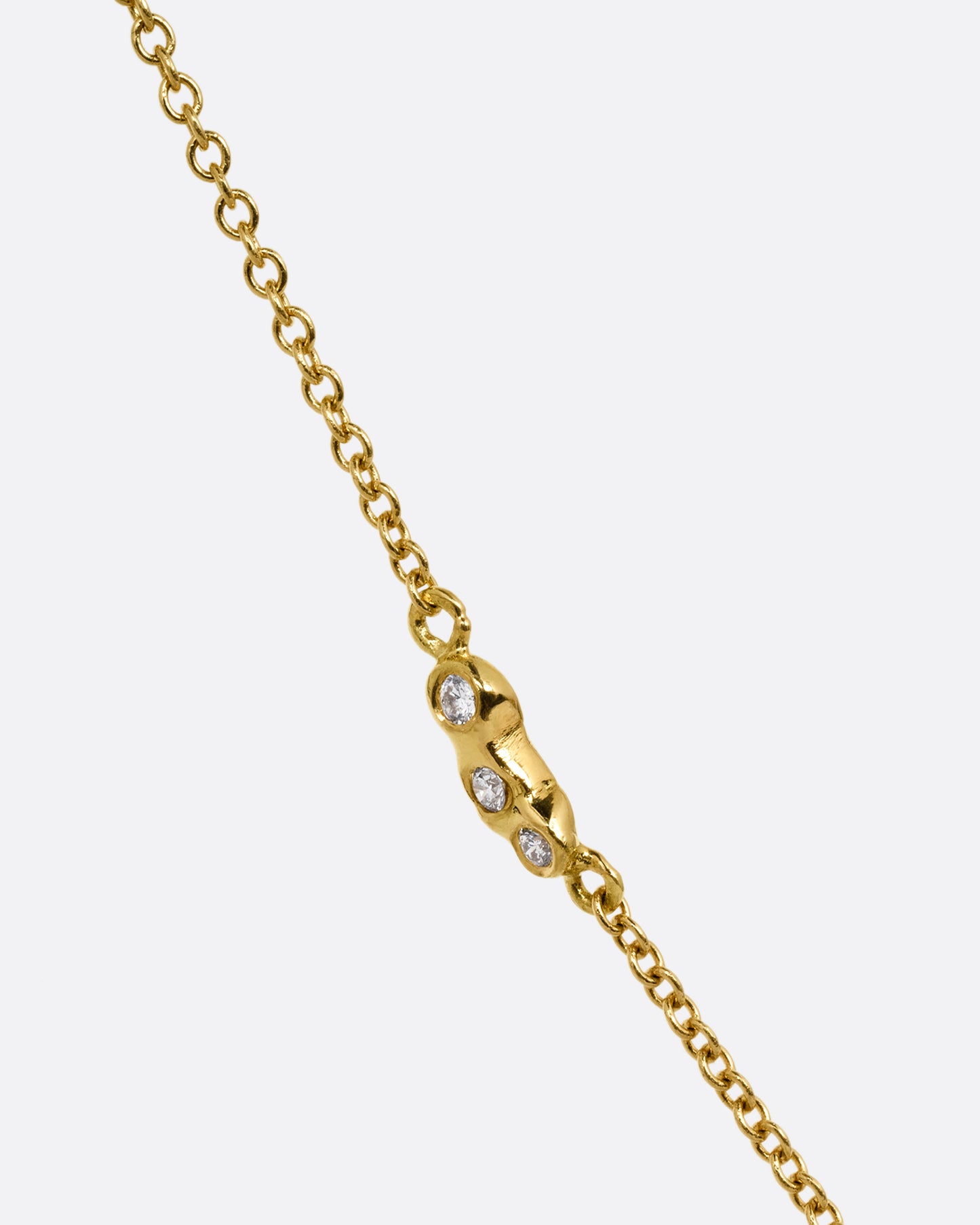 A close up of diamond detailing on a yellow gold cable chain. Shown diagonally from the front.