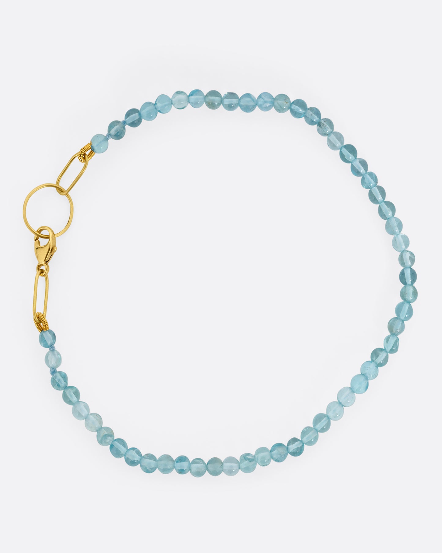 An apatite beaded bracelet with a yellow gold clasp. Shown from the top.