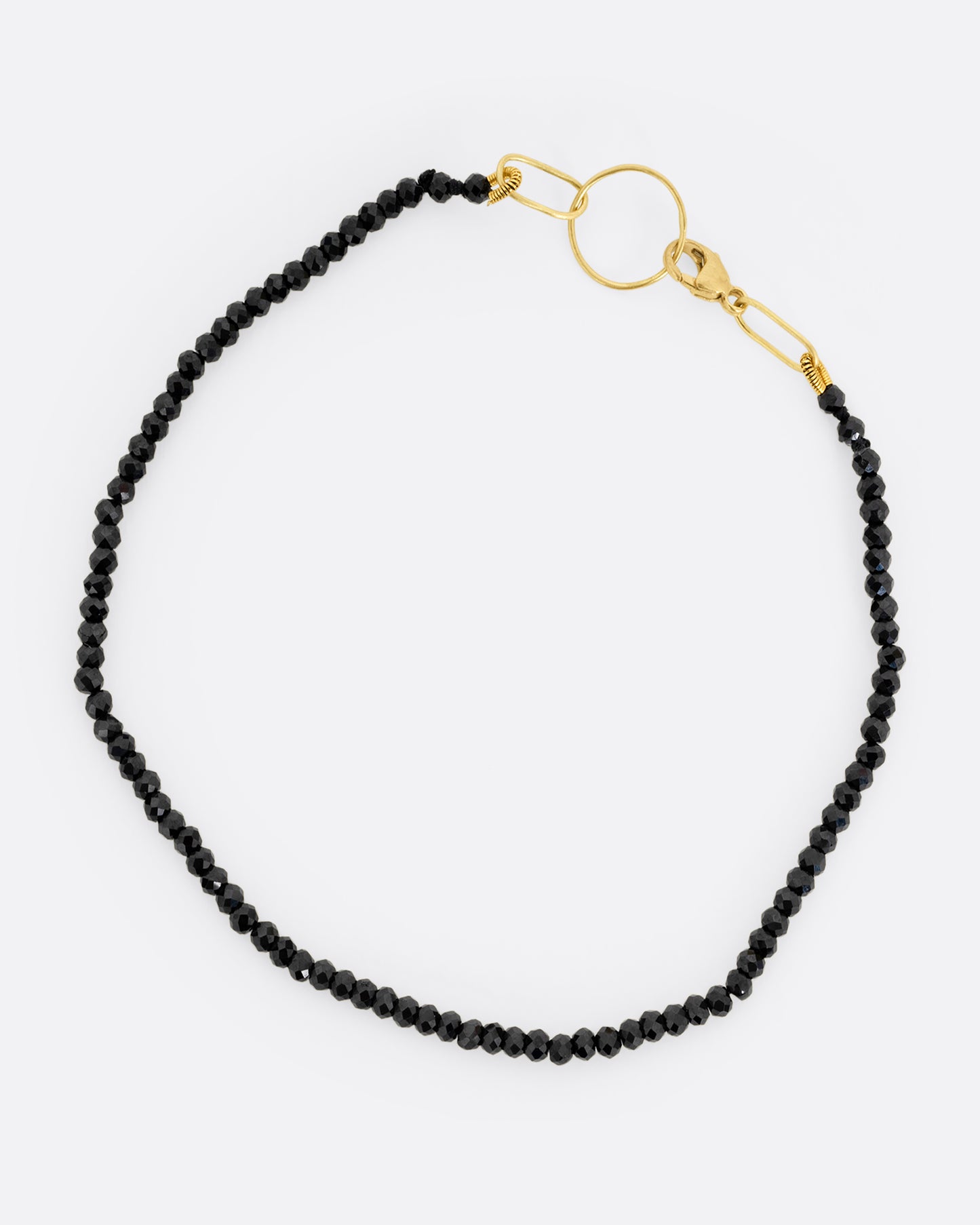 A black spinel beaded bracelet with a yellow gold clasp. Shown from the top.