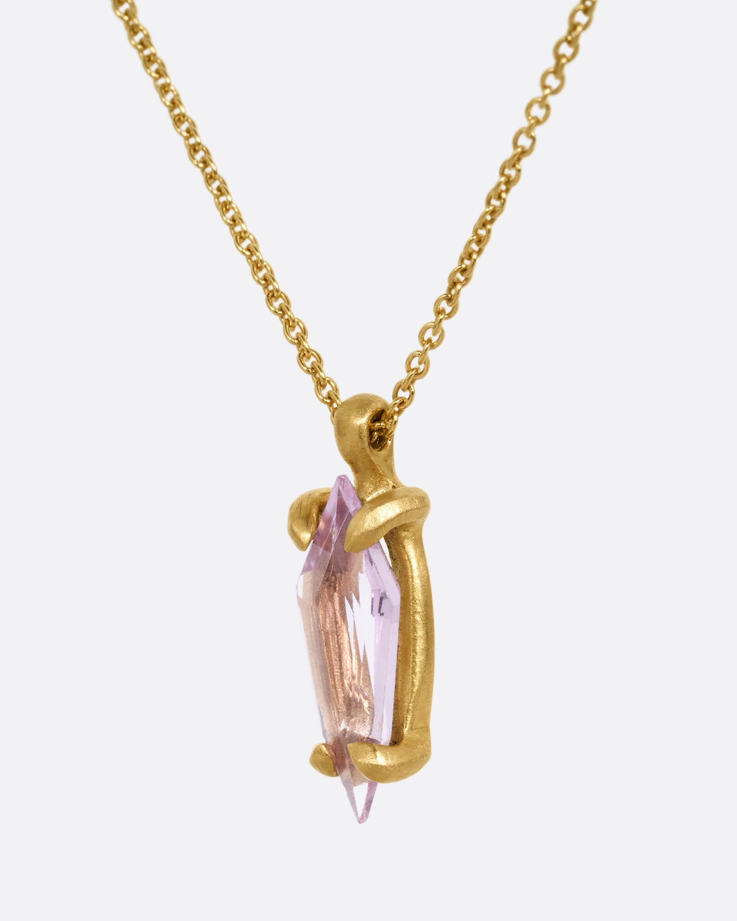A yellow gold cable chain necklace with a single pink sapphire pendant. Shown from the side.