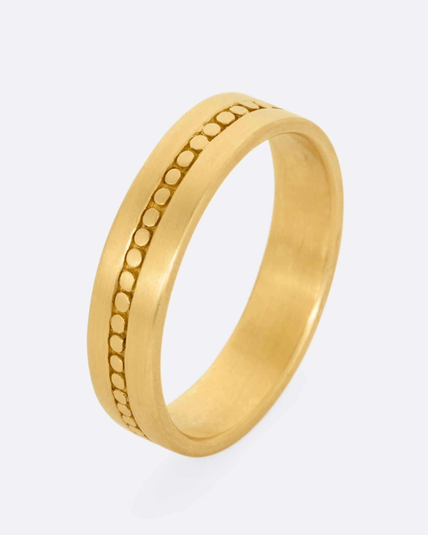 A yellow gold band with a center stripe of circles. Shown standing up from the front.
