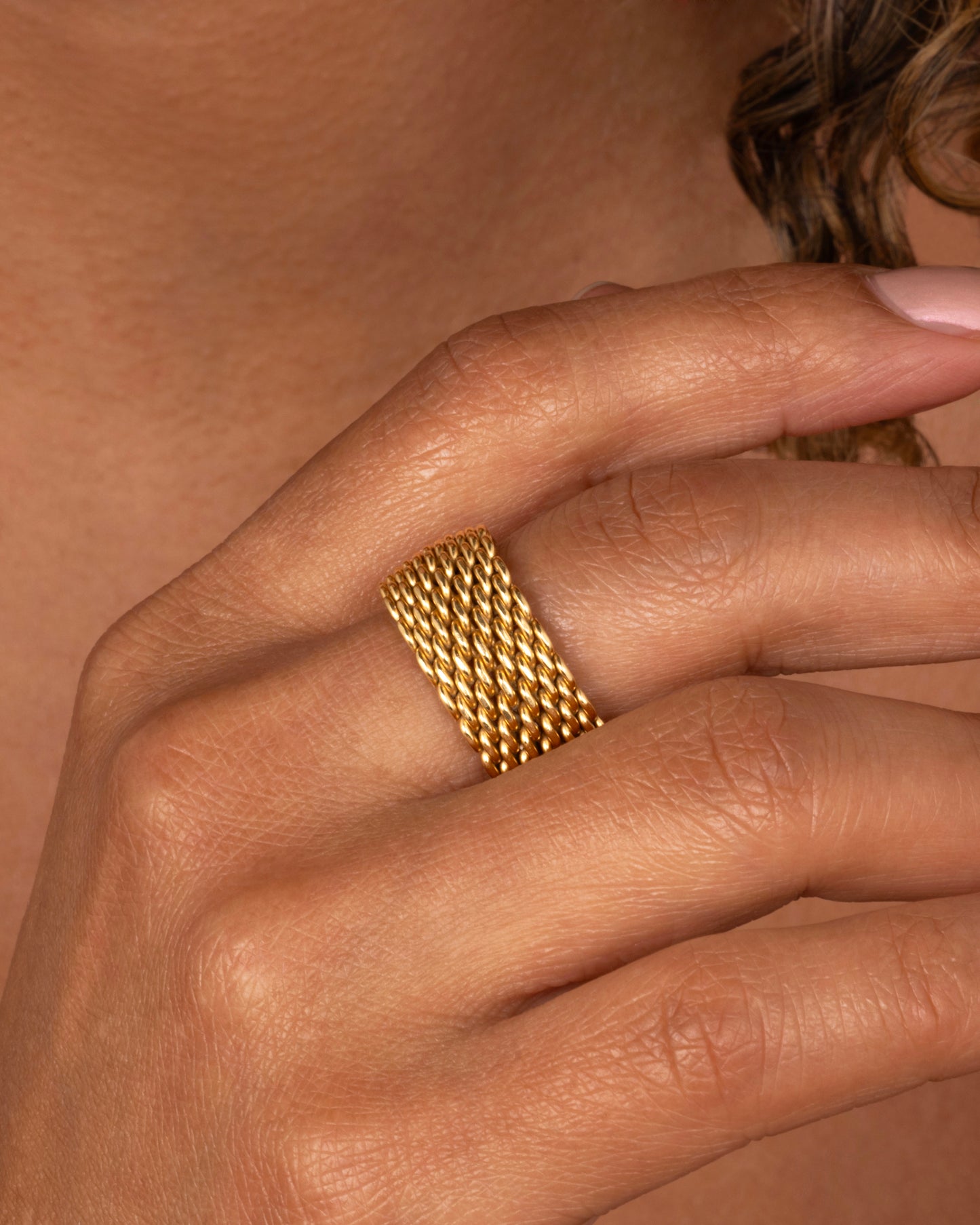 A yellow gold mesh Tiffany and Co. ring. Shown worn on a finger.