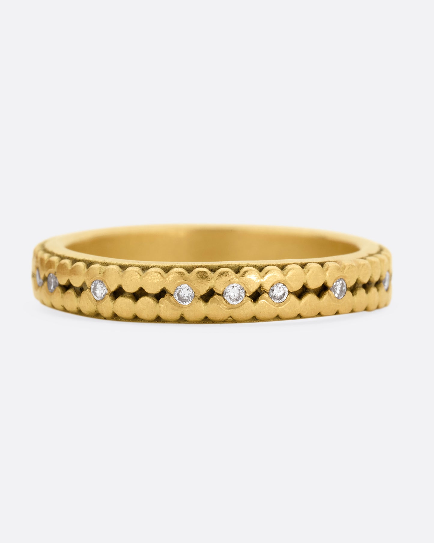 A yellow gold ring with two rows of dots and bezel set diamonds peppered along the center line. Shown from the front.