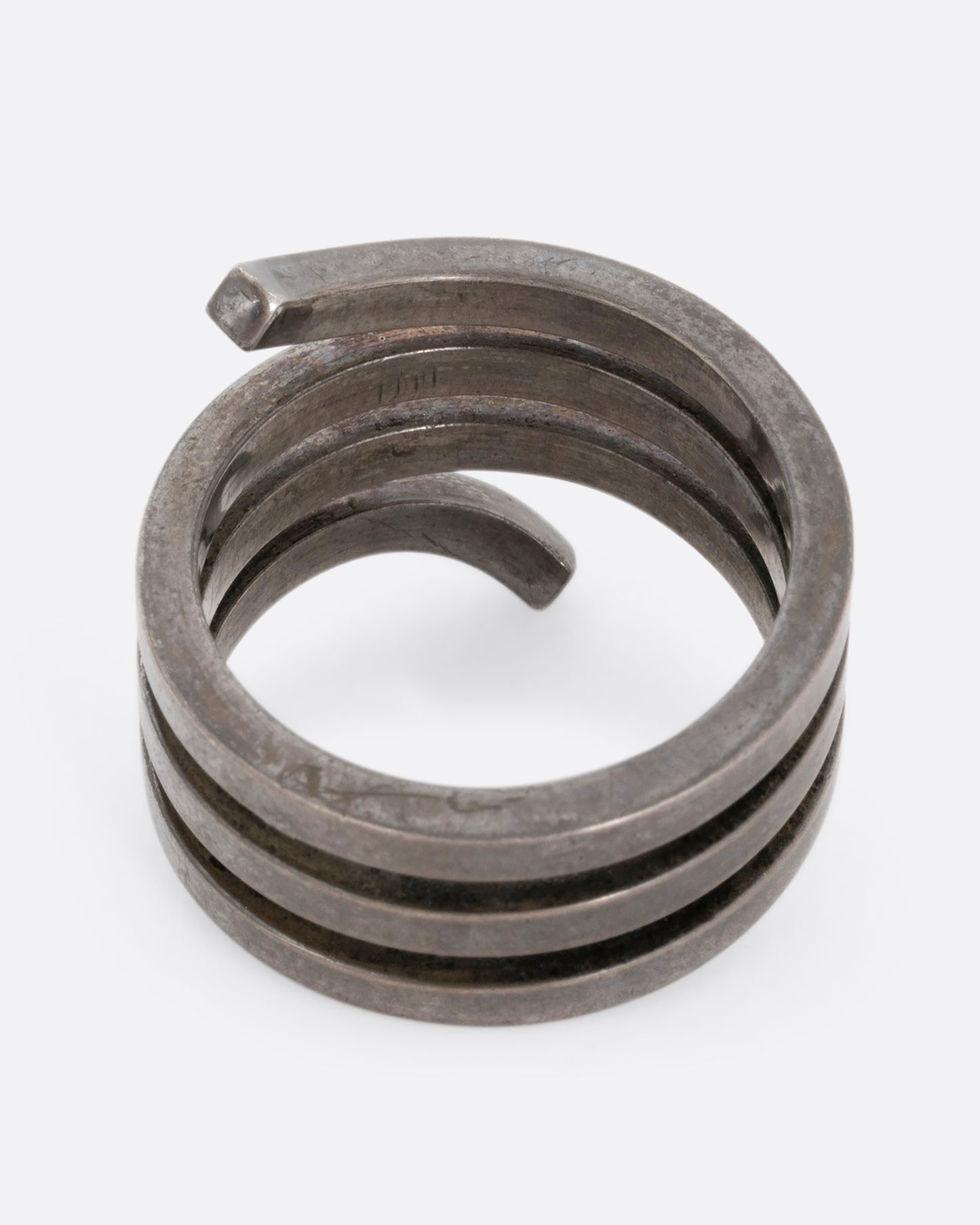 A silver ring with a coil silhouette. Shown from the top.