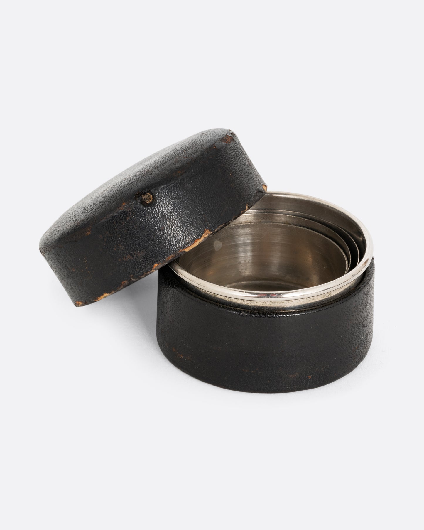 A silver collapsable cup in a leather case. Shown open from the front.