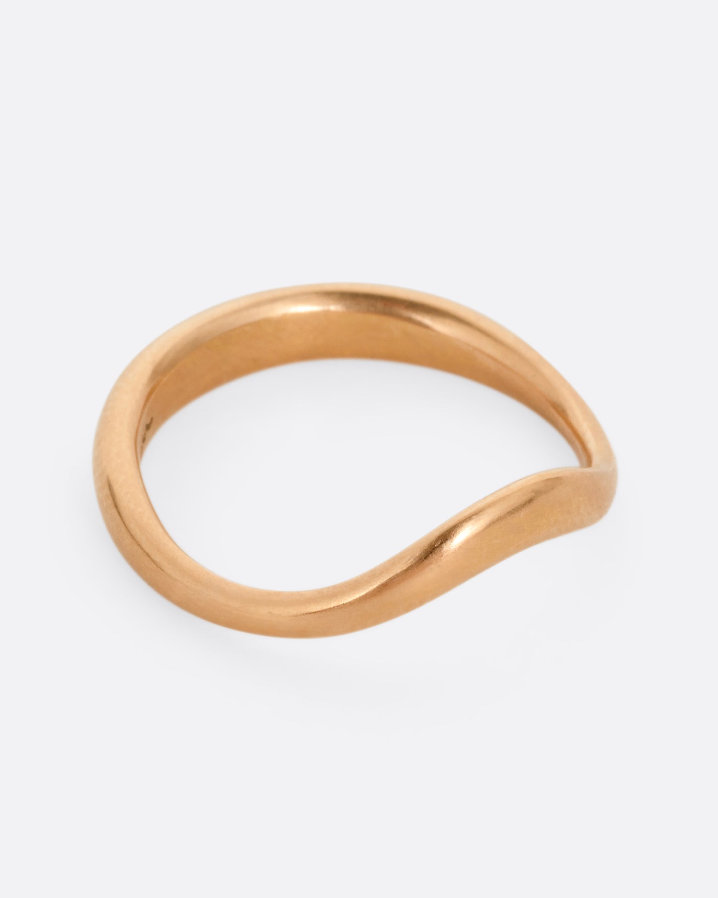A rose gold ring with a gentle curve in the front. Shown from the side.