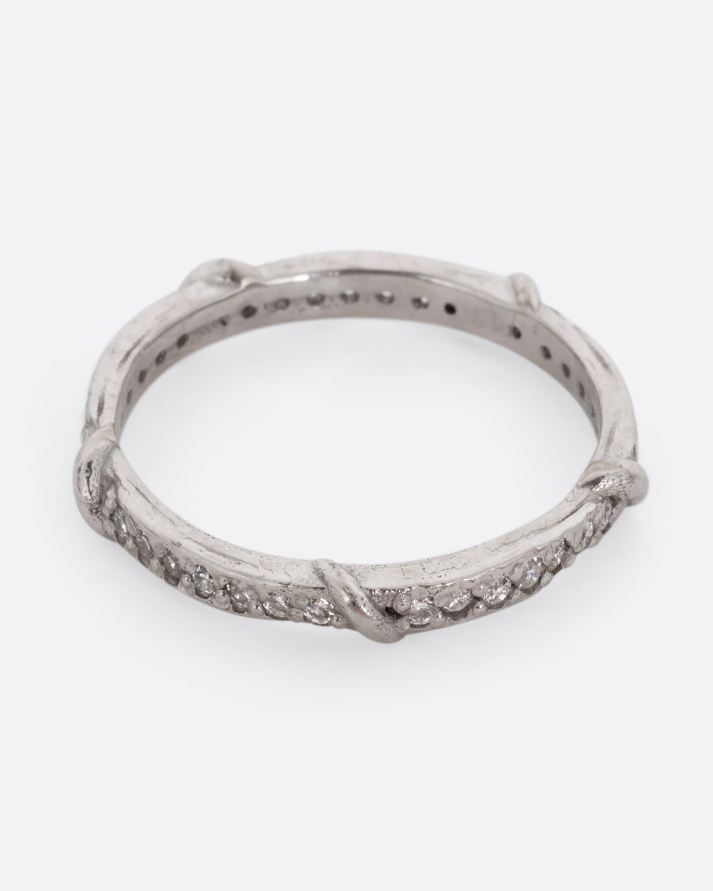 A platinum eternity band with vine detailing and brilliant white diamonds. Shown from the top.