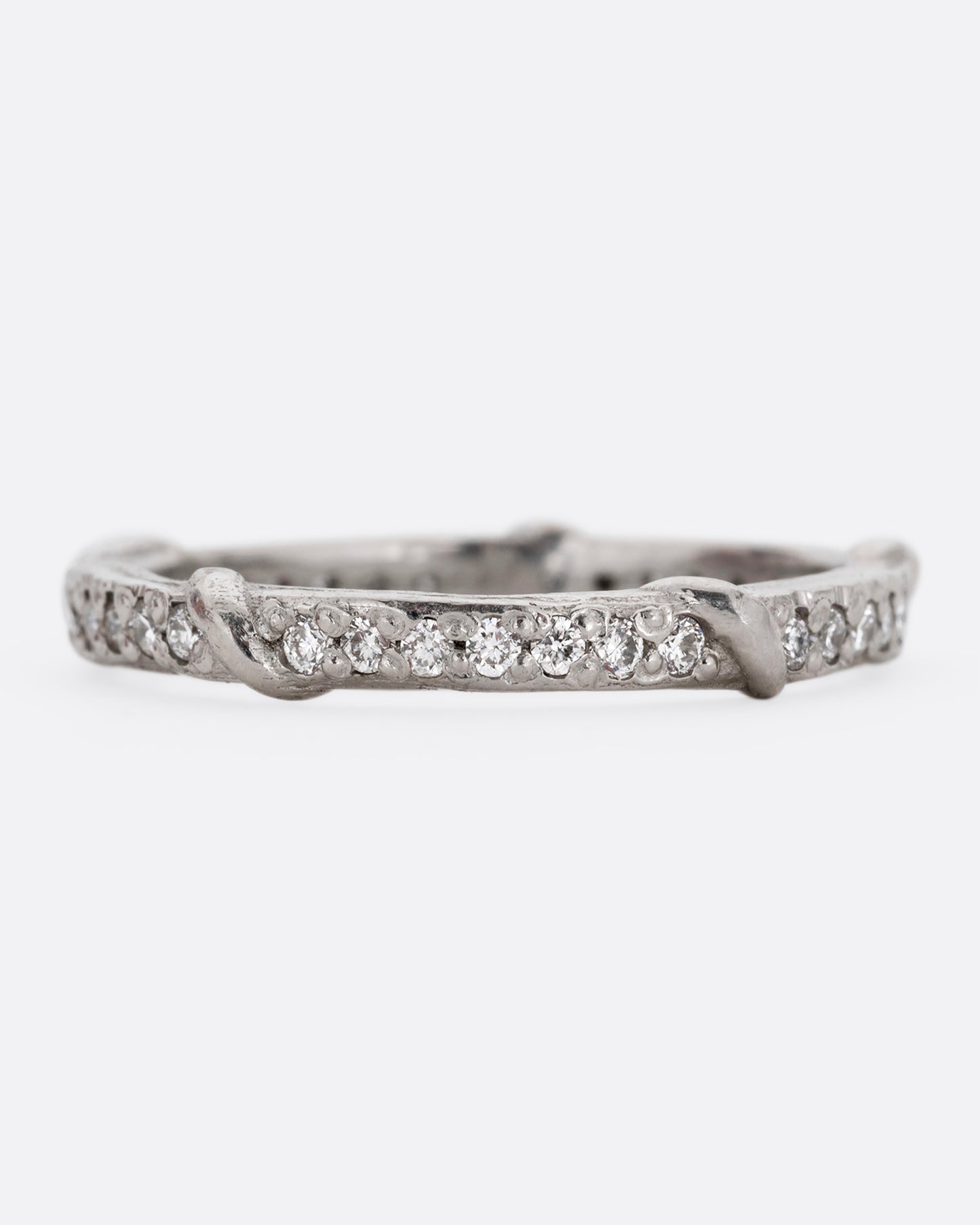 A platinum eternity band with vine detailing and brilliant white diamonds. Shown from the front.