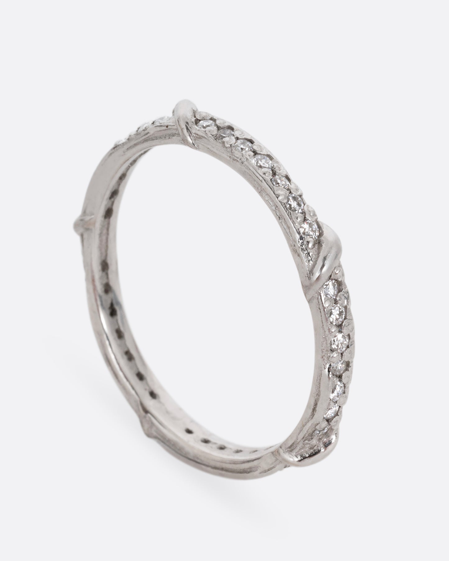 A platinum eternity band with vine detailing and brilliant white diamonds. Shown standing up from the side.