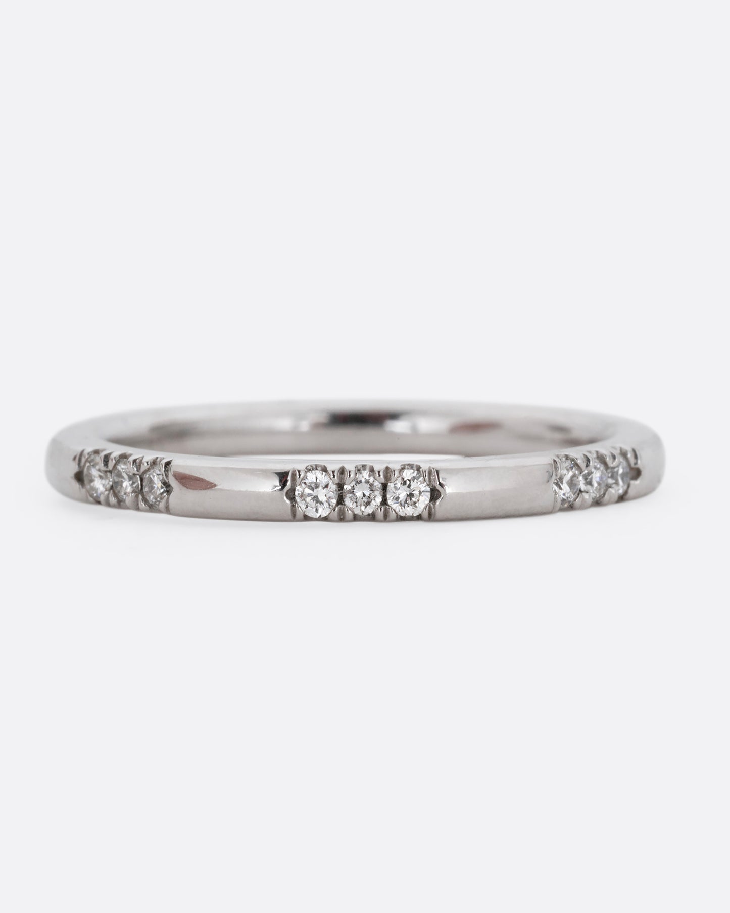 A platinum ring with stations of white diamonds. Shown from the front.