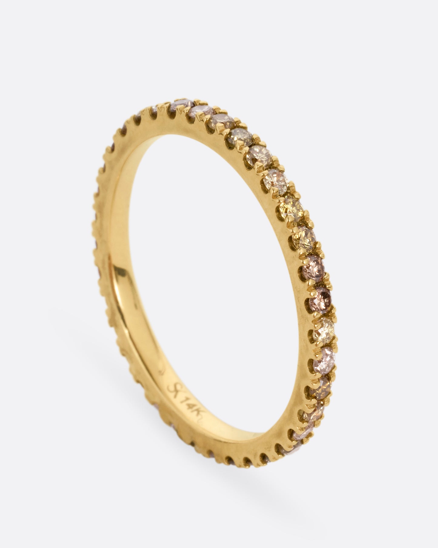 A yellow gold eternity band with olive, champagne, and cognac diamonds. Shown standing up from the front.