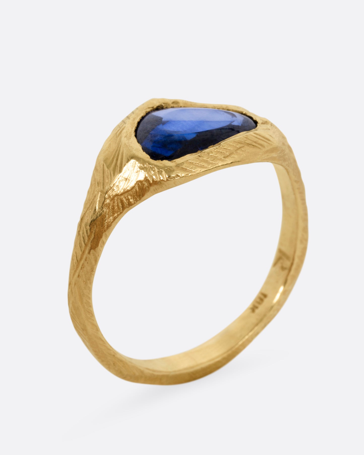 A yellow gold ring with a blue sapphire, shown from the side standing up.