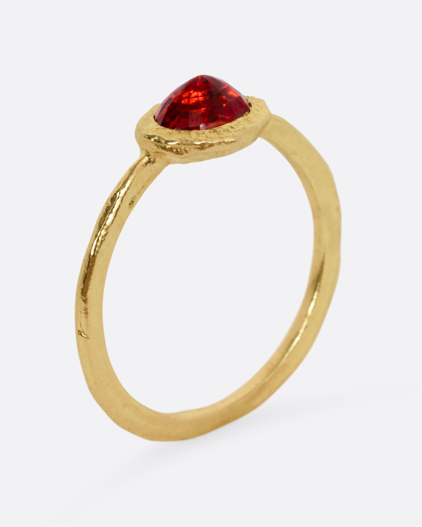 A yellow gold ring with a red sapphire, shown from the side standing up.