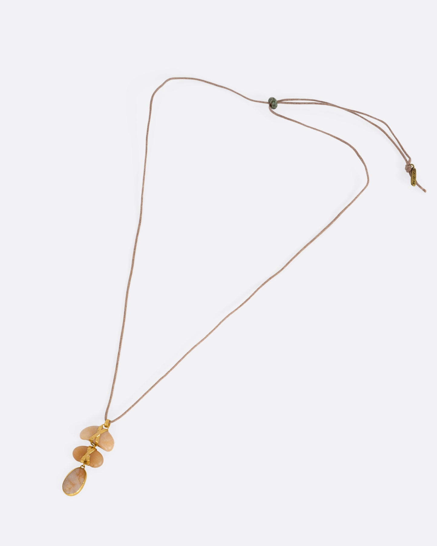 A yellow gold pendant with three polished pebbles on a cord, shown from the front.