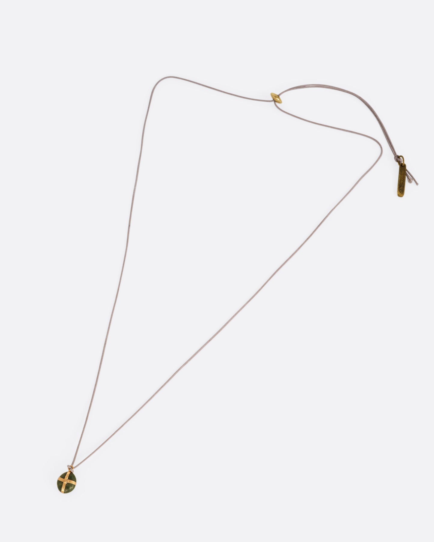 A Japanese river pebble pendant wrapped in yellow gold and hanging from a cord, shown from the front.