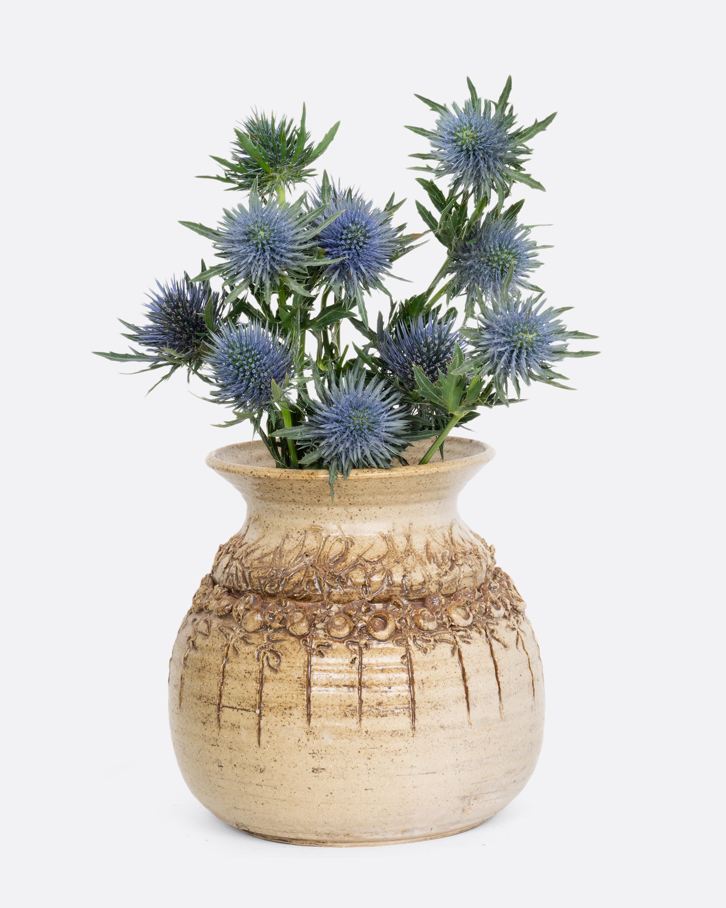 Brown ceramic three dimensional textured vase. Shown with flowers.
