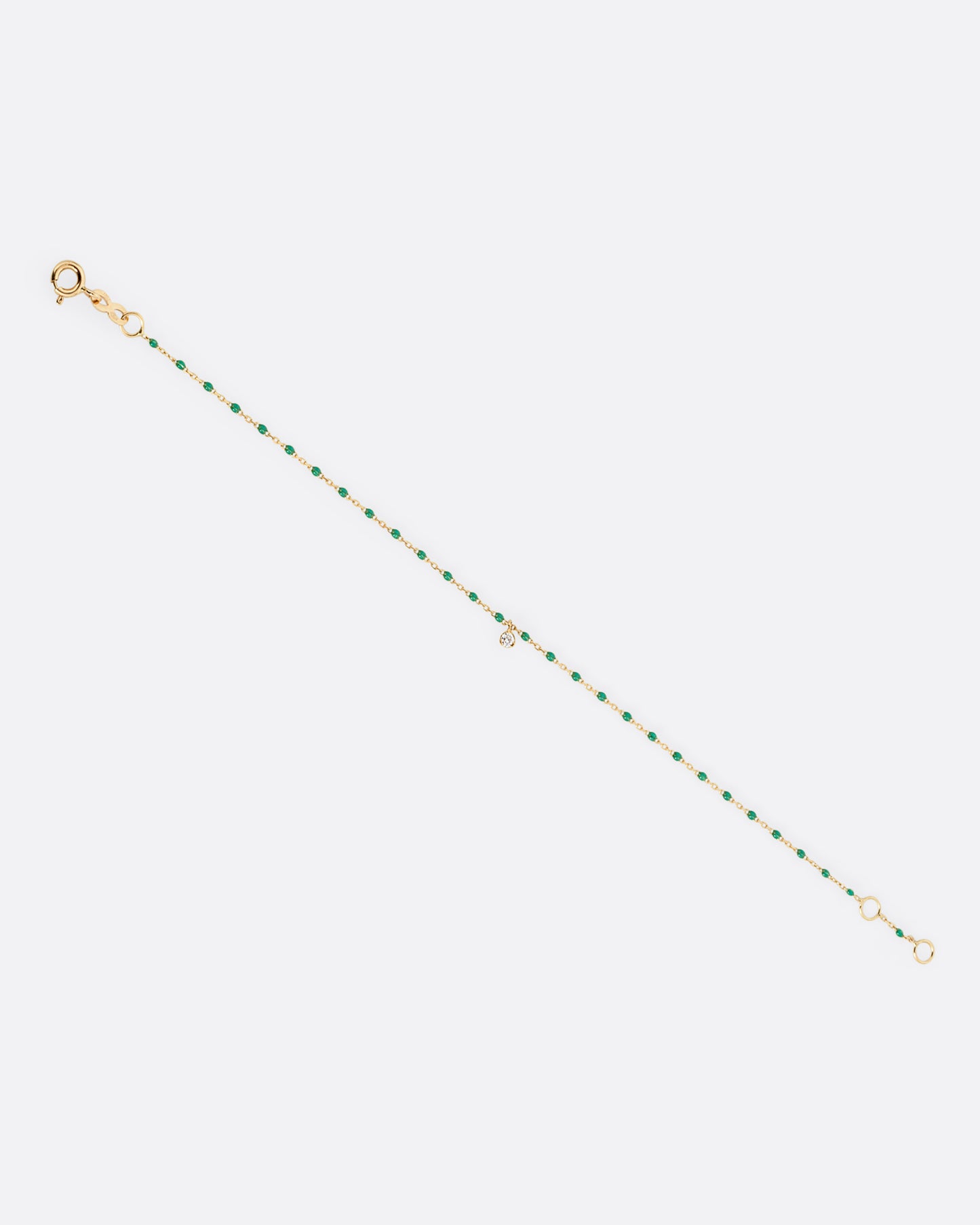 A yellow gold cable chain bracelet with green resin droplets throughout and a single diamond charm. Shown from the front.