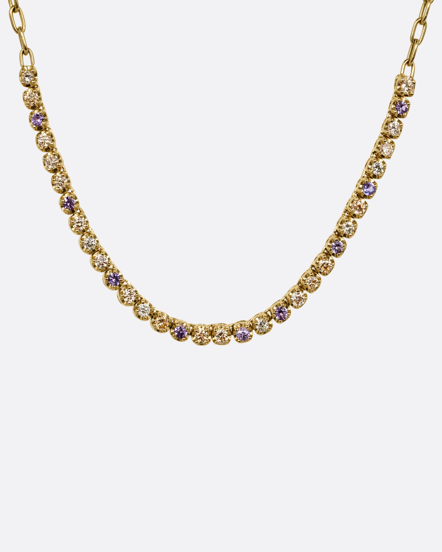 A yellow gold cable chain necklace with peach and yellow diamonds and purple sapphires in a 'partial tennis' setting. Shown from the front.