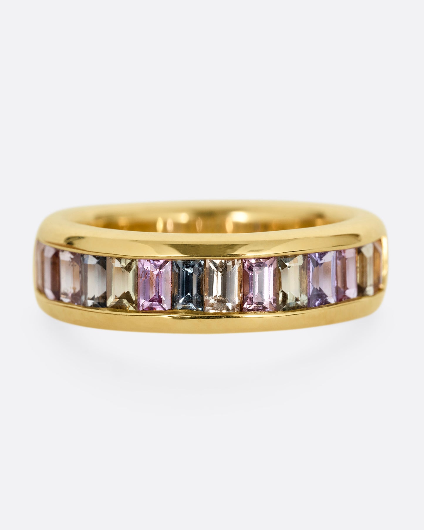 A yellow gold ring with channel set multicolored sapphires. Shown from the front.