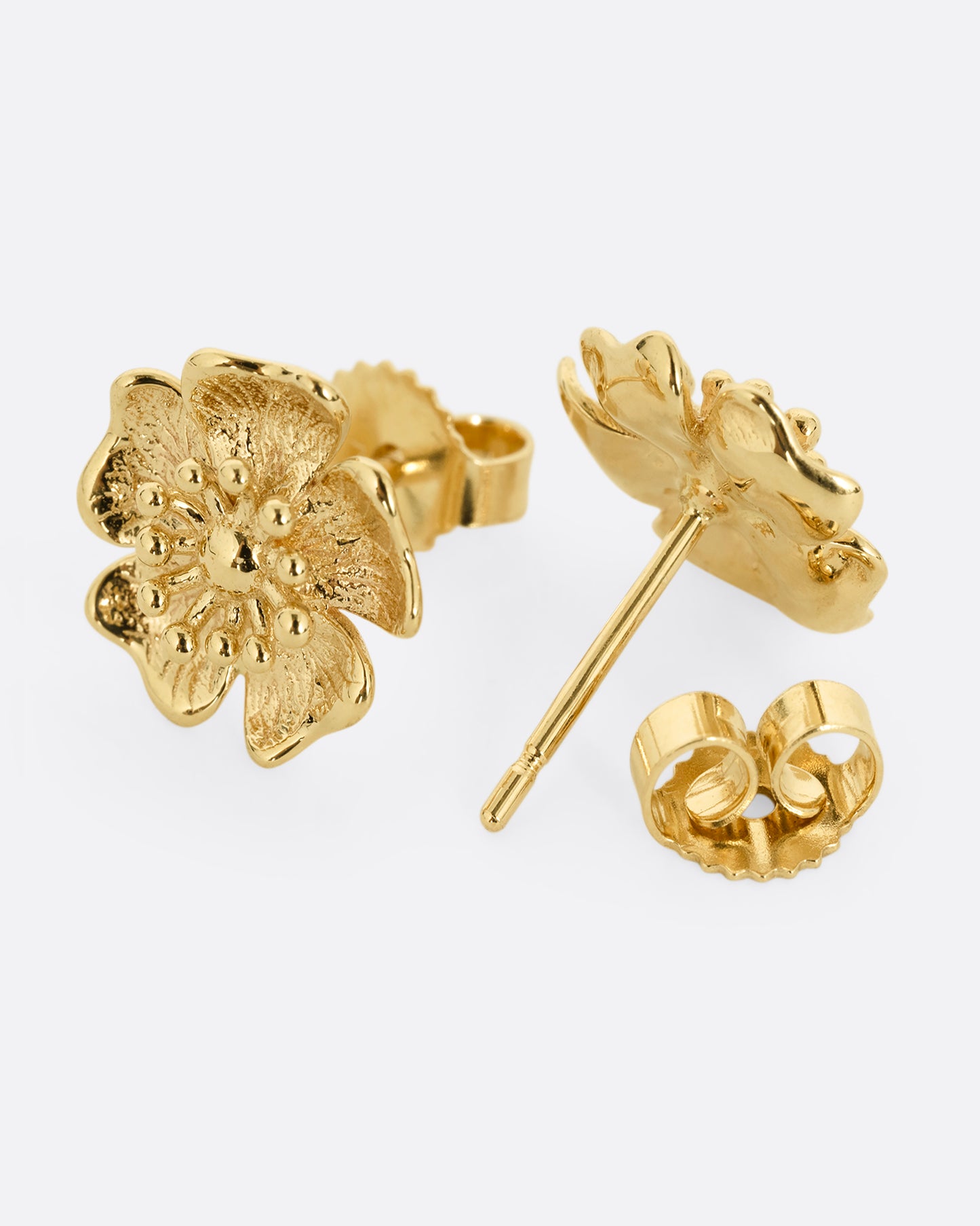 A pair of yellow gold flower stud earrings. One earring is shown from the front, the other is shown open from the back.
