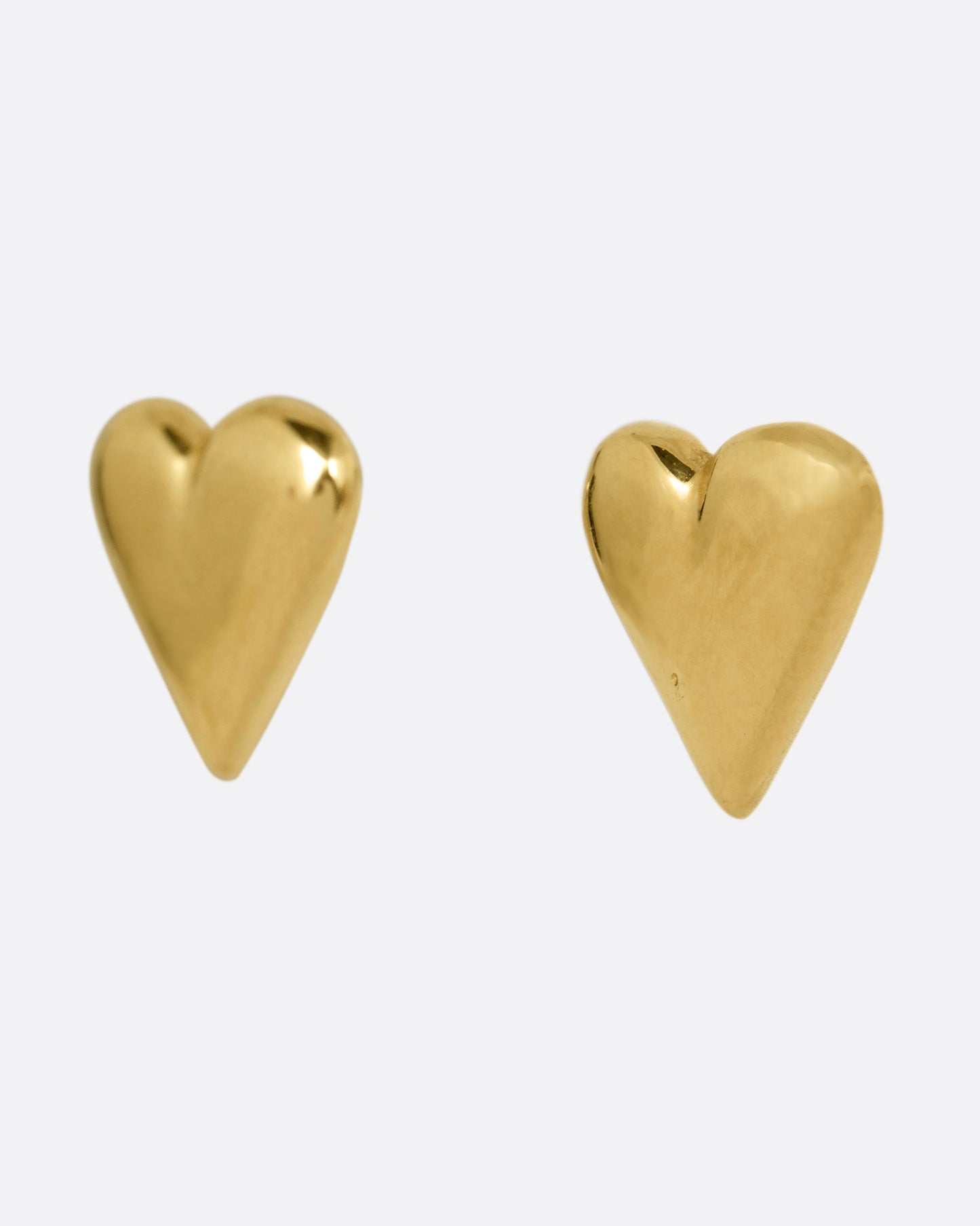 A pair of yellow gold heart earrings. Shown from the side.
