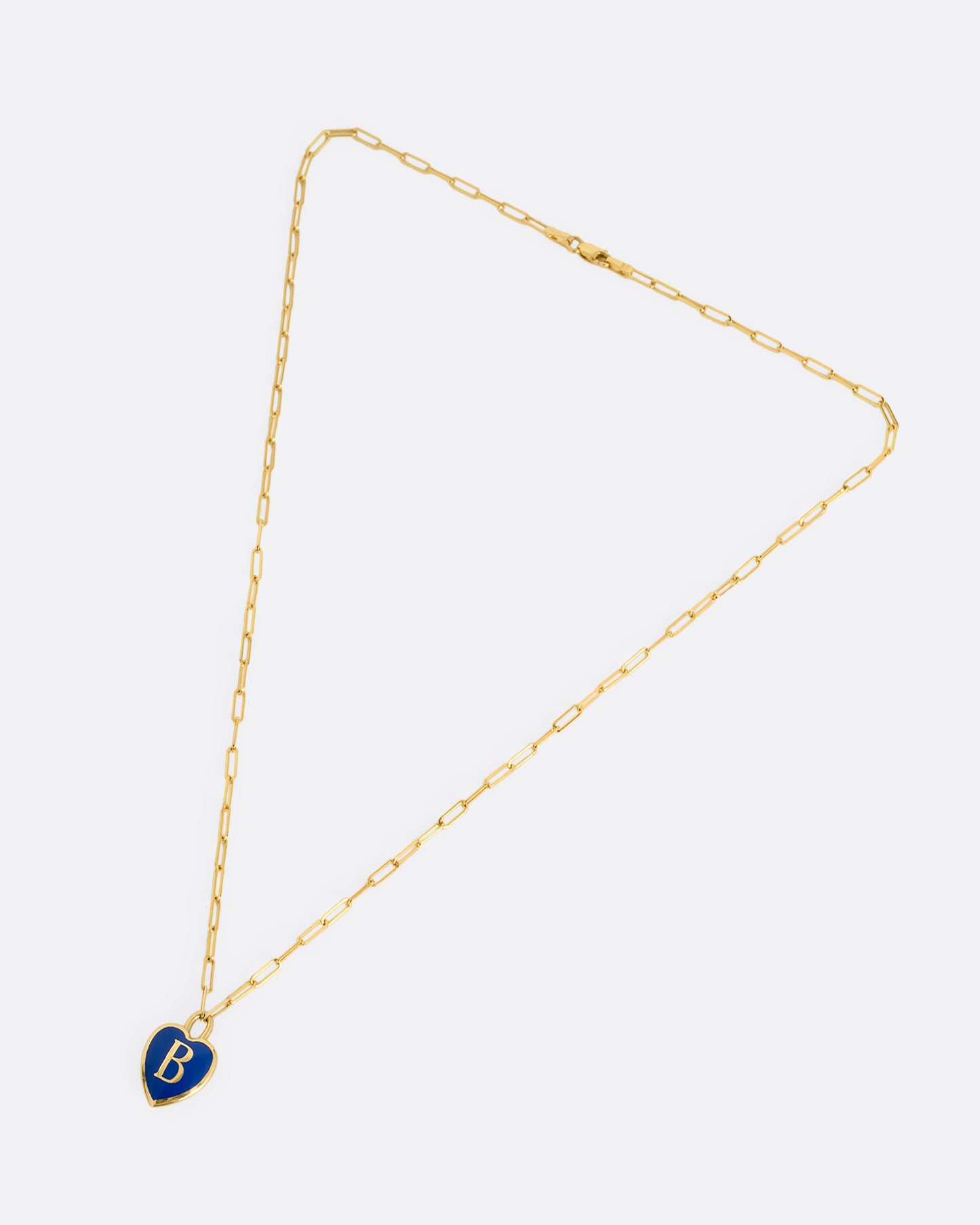 A yellow gold paperclip chain necklace with a black enamel heart shaped N pendant. Shown closed lying flat at an angle from the front.