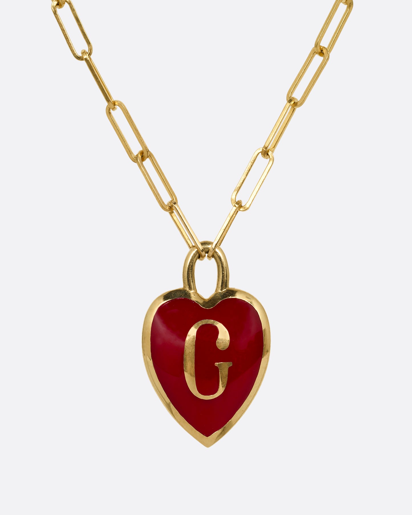 A yellow gold paperclip chain necklace with a red enamel heart shaped G pendant. Shown from the front.